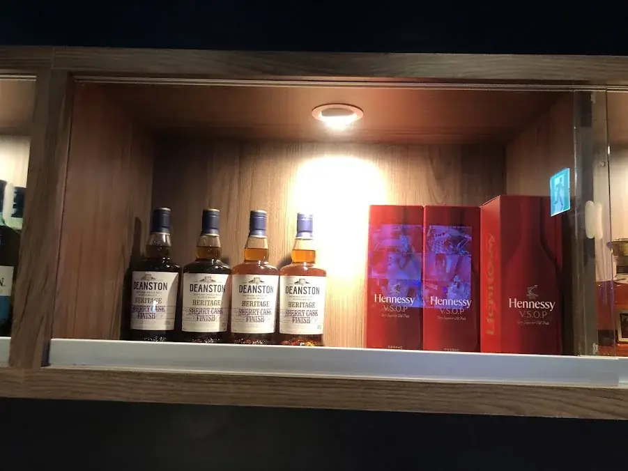 日出商務會館木質酒櫃內陳列瓶裝威士忌與紅色酒盒，上方設有照明